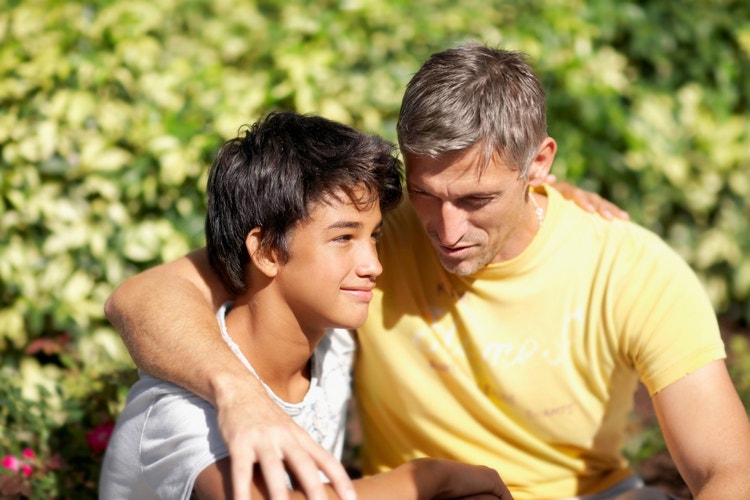 A dad with his arm around his son