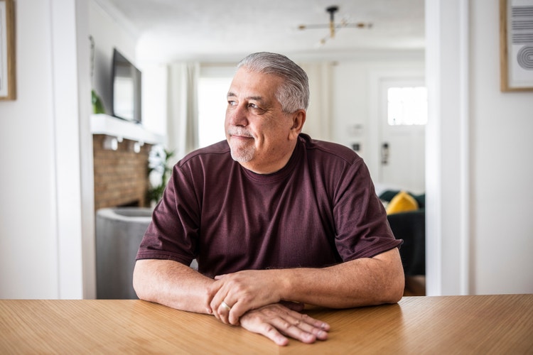 Older adult male seated with a serious expression