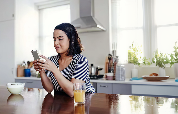 Woman seated in kitchen scrolling her phone