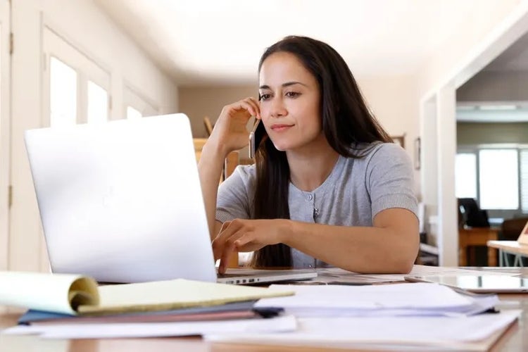 a woman on her phone at a laptop