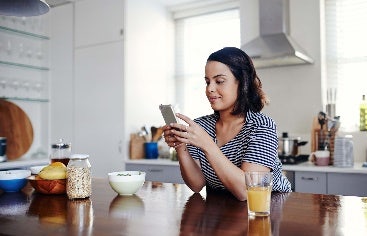 Woman seated in kitchen scrolling her phone