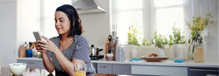 Woman seated in kitchen scrolling her phone